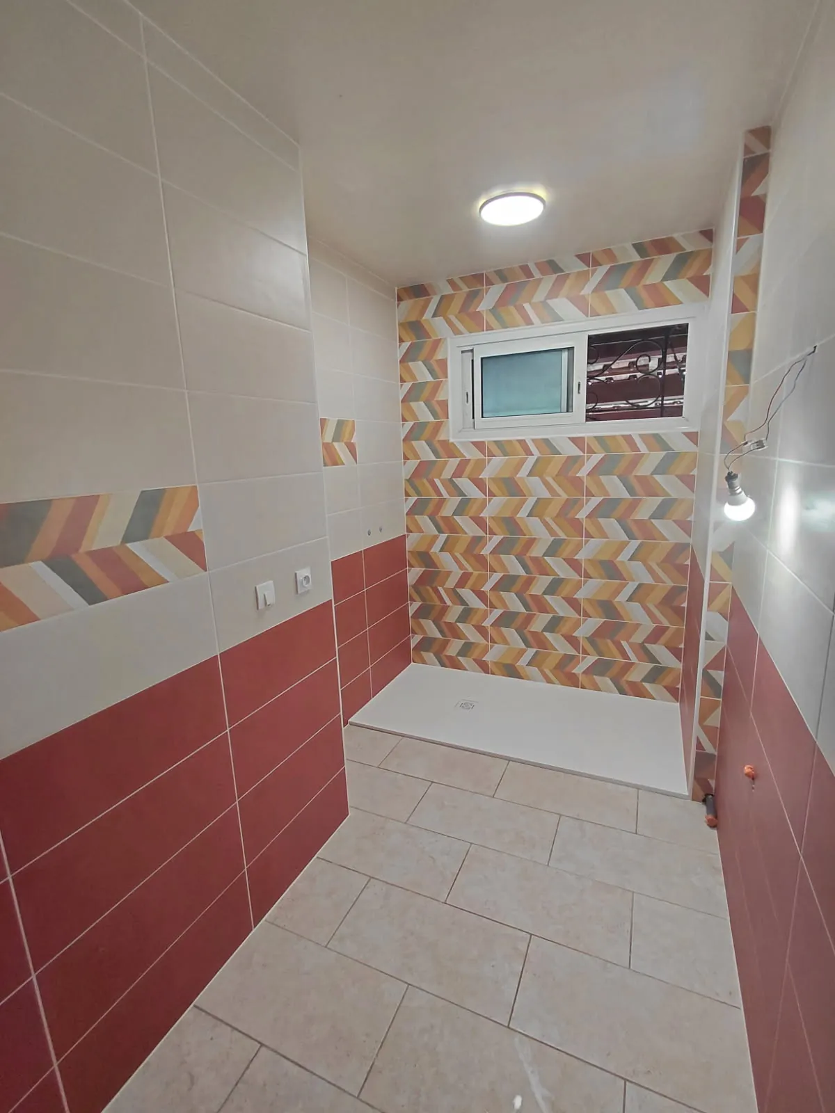 Salle de bain rénovée, sol carrelé à motifs et mur d'accent